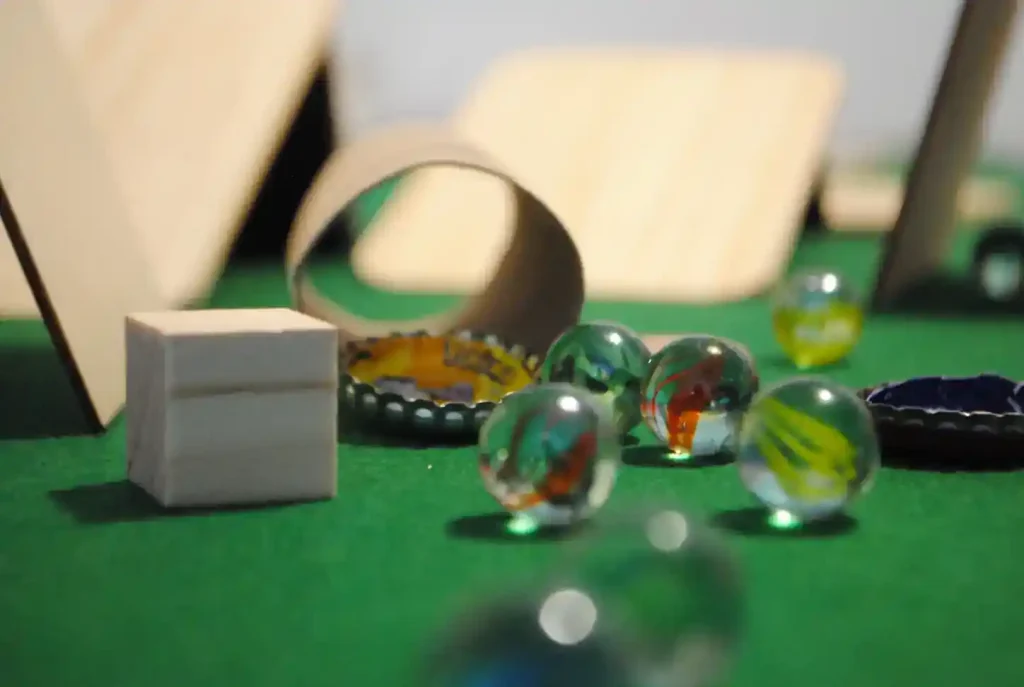 La imagen muestra una variedad de materiales relacionados con los juegos tradicionales: chapas, canicas y otros elementos.