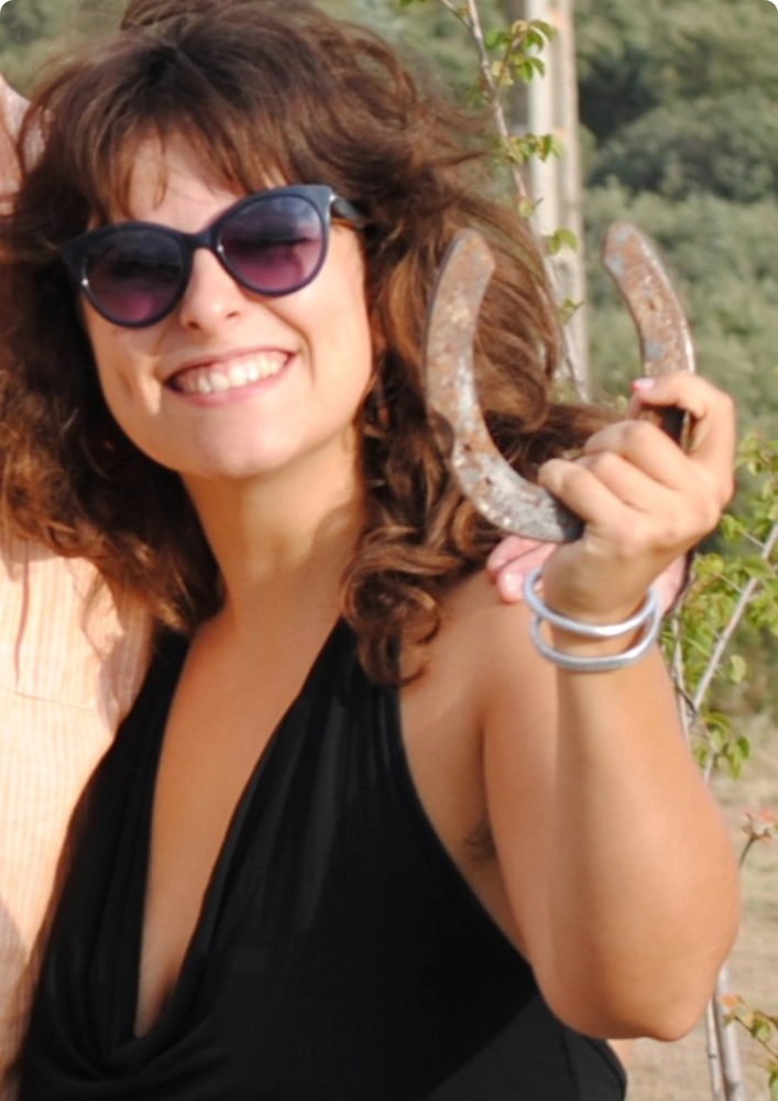 Violeta Gonzalez sosteniendo una herradura en la mano a la altura de la cara. 
